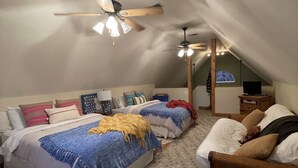 Une chambre avec deux lits, un ventilateur de plafond et un petit bureau avec une lampe.