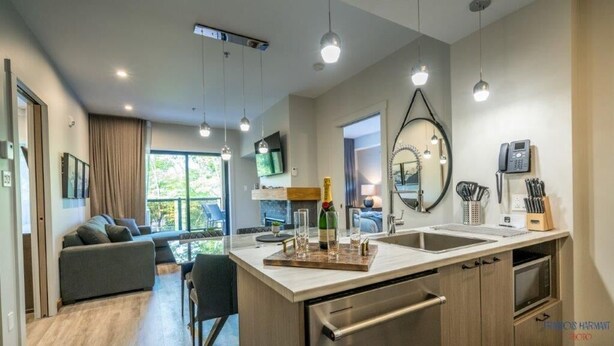 Una cocina moderna con una isla central, una zona de comedor con sofá y un amplio ventanal que proporciona luz natural.
