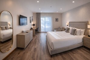 Una habitación de hotel moderna con una cama grande, un escritorio, una silla, un aparador y un televisor.