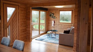 L’intérieur d’un chalet en bois comprend un coin repas, un canapé et une petite table sur laquelle est posé un vase.