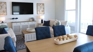 A modern living room with a sofa, chairs, a TV, and a dining table with decorative items.