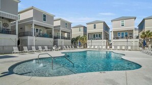 A pool area with lounge chairs, a pool, and multi-story buildings with balconies.