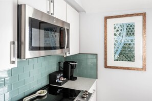Une cuisine équipée d’un four à micro-ondes en acier inoxydable, d’une machine à café et d’une œuvre d’art encadrée accrochée au mur.