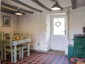 A room with a dining table set for breakfast, a green chest freezer, and a white door with a heart decoration. - 2 bedroom accommodation in Carno (Carno)