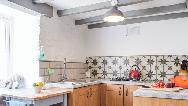 Una cocina con un lavamanos, estufa, armarios de madera y un salpicadero decorado.