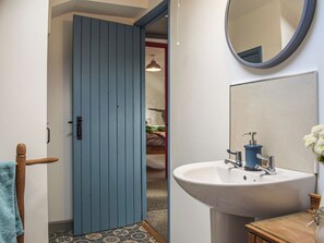 A bathroom with a blue door, a white sink, a mirror, and a towel rack.