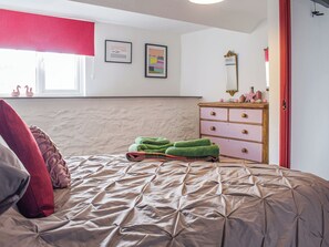 A bedroom with a bed, a dresser, a window, and wall decorations.