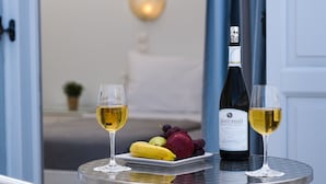 Una mesa con una botella de vino y dos copas, un plato de frutas y una silla.