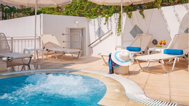 Zona de piscina con sillones de descanso, sombrillas y montañas al fondo.