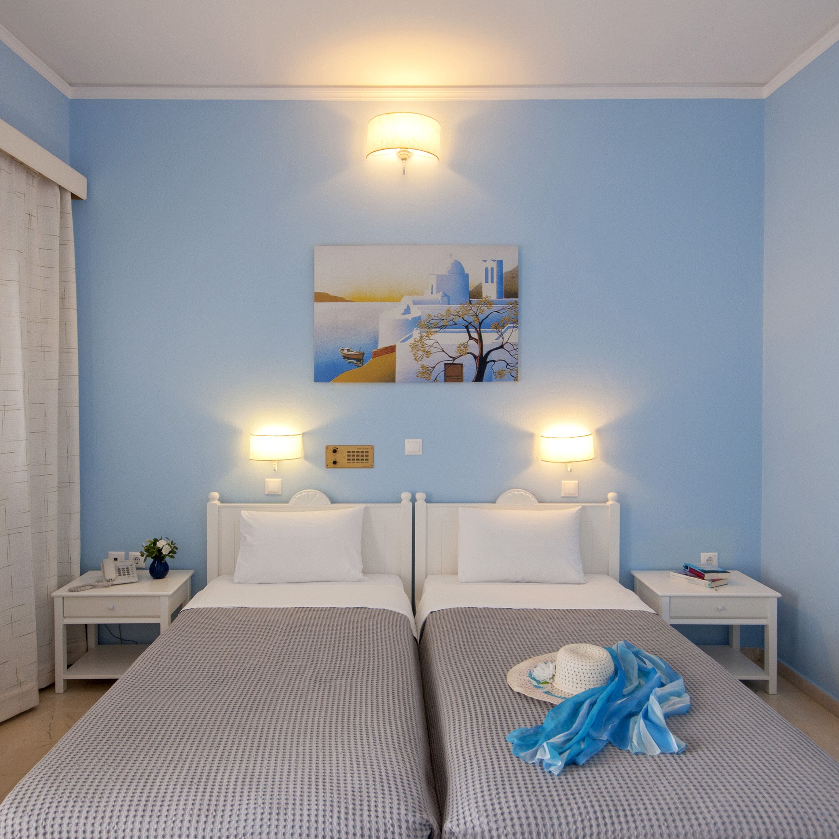 A hotel room with two beds, a painting on the wall, and bedside lamps.