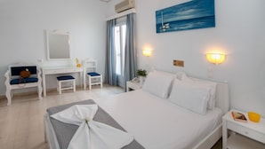 Habitación de hotel con cama, escritorio, silla, mesita de noche y ventana con cortinas.