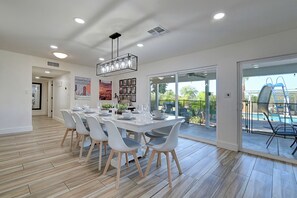 A modern dining area with a large table, chairs, and a ceiling light fixture.