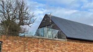 Een gebouw van baksteen met een schuin dak en een glazen uitbouw.