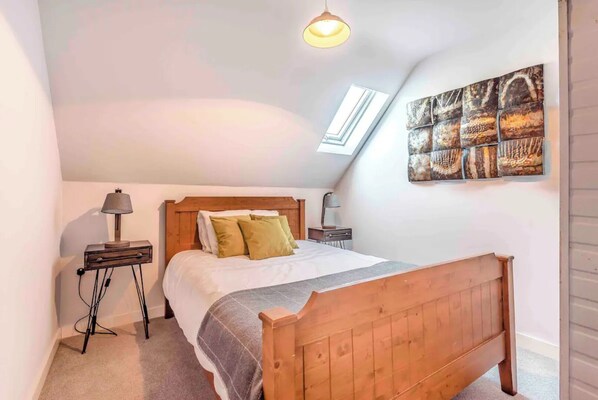 A bedroom with a wooden bed, a nightstand, a lamp, and a skylight. - Riverside Coach House, Hunton Yalding, Maidstone ME15 ORQ (Hunton)