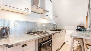 Een moderne keuken met een gasfornuis, oven en aanrechtbladen van roestvrij staal.