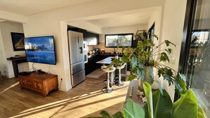 Et moderne køkken med et stort køleskab, et spiseområde med bord og stole, samt et tv ophængt på væggen.