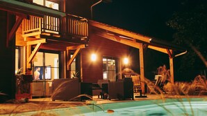 Et toetagers træhus med balkon, swimmingpool og udendørs møbler.
