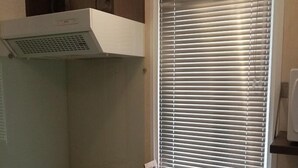 A compact kitchen with a gas stove, a sink, and a window with blinds. - La Roque d'Anthéron - Mobil-home - 6 pers - 3 bdrms - Swimming pool (La Roque-d'Anthéron)