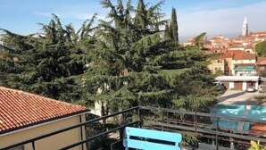 Una terrazza sul tetto con un tavolo e sedie blu, una piscina e vista su alberi e palazzi.