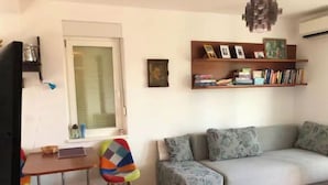 Un soggiorno accogliente con un divano, una poltrona colorata, un tavolino e una libreria.