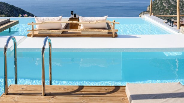 A poolside area with a wooden deck, lounge chairs, and a view of the sea. - SWIM UP SUITE with direct access to the infinity pool and stunning sea view (Alonissos)