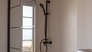A glass-enclosed shower area with a handheld showerhead and a wall-mounted faucet. - SWIM UP SUITE with direct access to the infinity pool and stunning sea view (Alonissos)