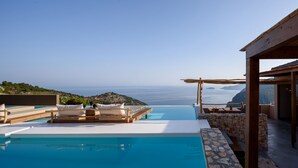 A infinity pool with a view of the sea and a wooden deck with lounge chairs. - SWIM UP SUITE with direct access to the infinity pool and stunning sea view (Alonissos)