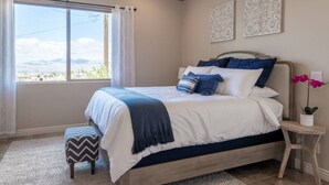 A bedroom with a large bed, a view of the outdoors, and decorative wall art. - Lake View Oasis Pool/Spa+Boat Garage+Ice Machine (Lake Havasu City)