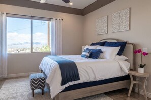 A bedroom with a large bed, a view of the outdoors, and decorative wall art. - Lake View Oasis Pool/Spa+Boat Garage+Ice Machine (Lake Havasu City)