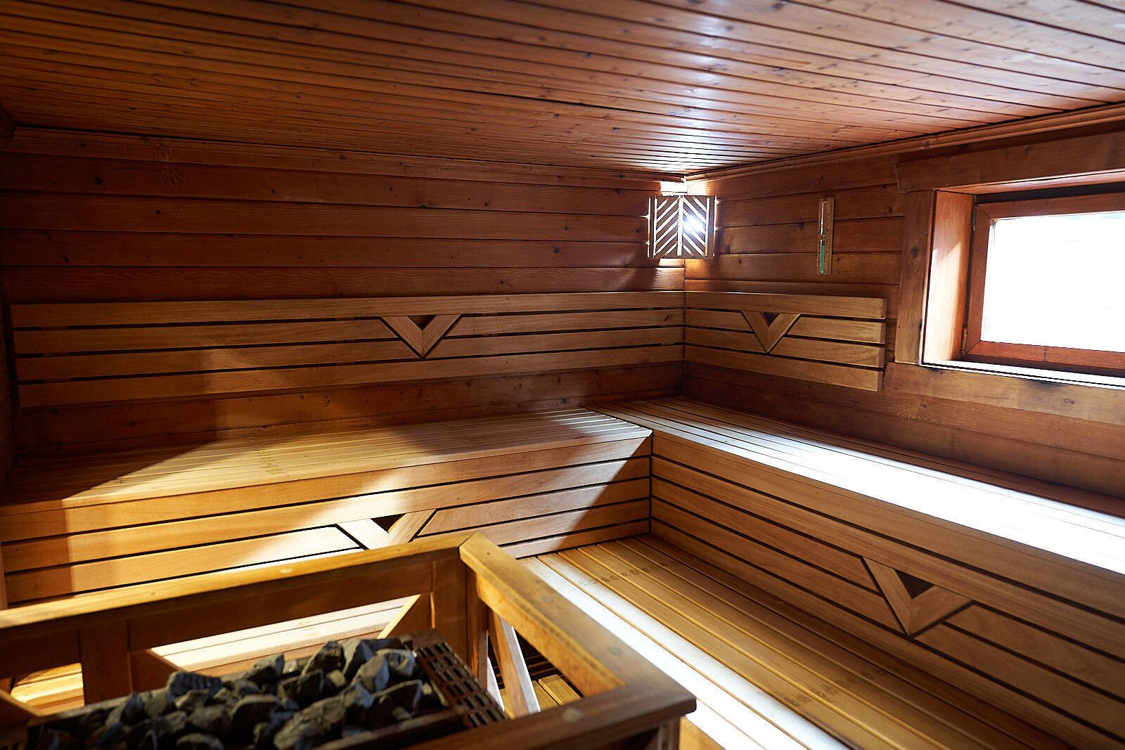A wooden cabin interior with a bench and a window.