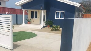 A residential house with a blue exterior, a front porch, and a small garden area.