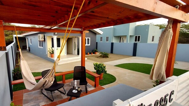 A covered outdoor seating area with a hammock, chairs, and a small table.