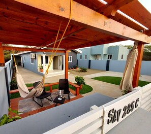 Un espace extérieur abrité, aménagé avec un hamac, des chaises et une petite table.