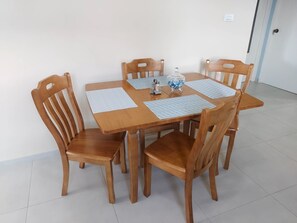 Una mesa de madera con cuatro sillas, un tarro de vidrio y dos individuales.