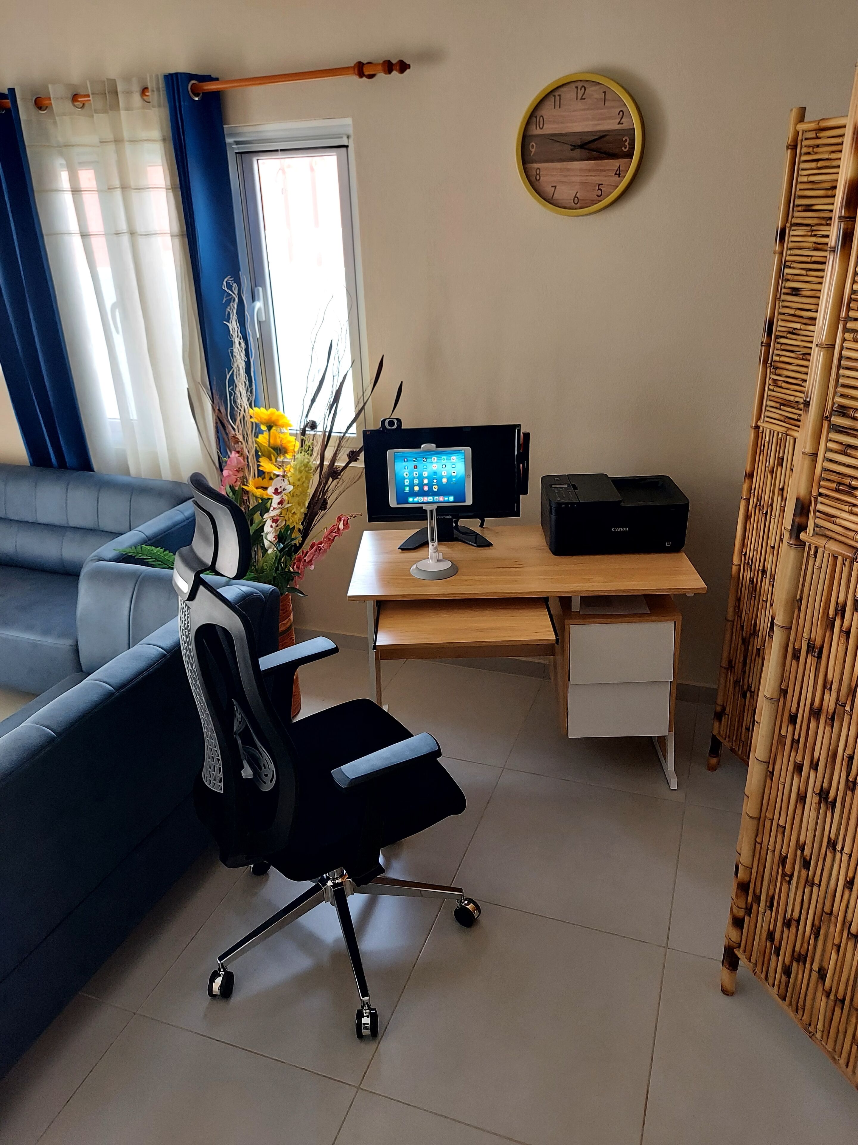 A modern office space with a desk, computer, printer, and a blue sofa.