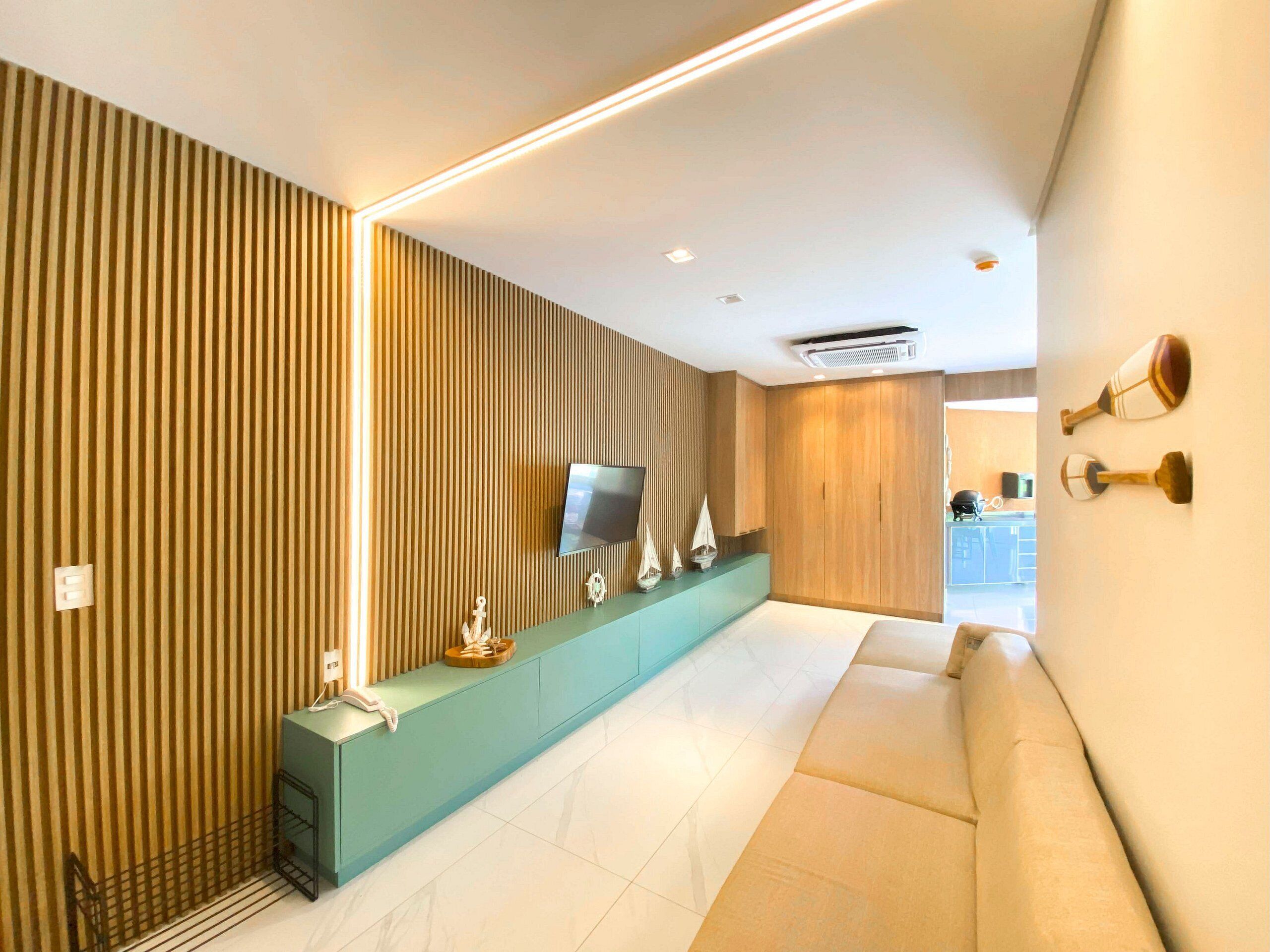 Een moderne hotellobby met een receptiebalie, een flatscreen televisie, een houten garderobe en een zithoek.