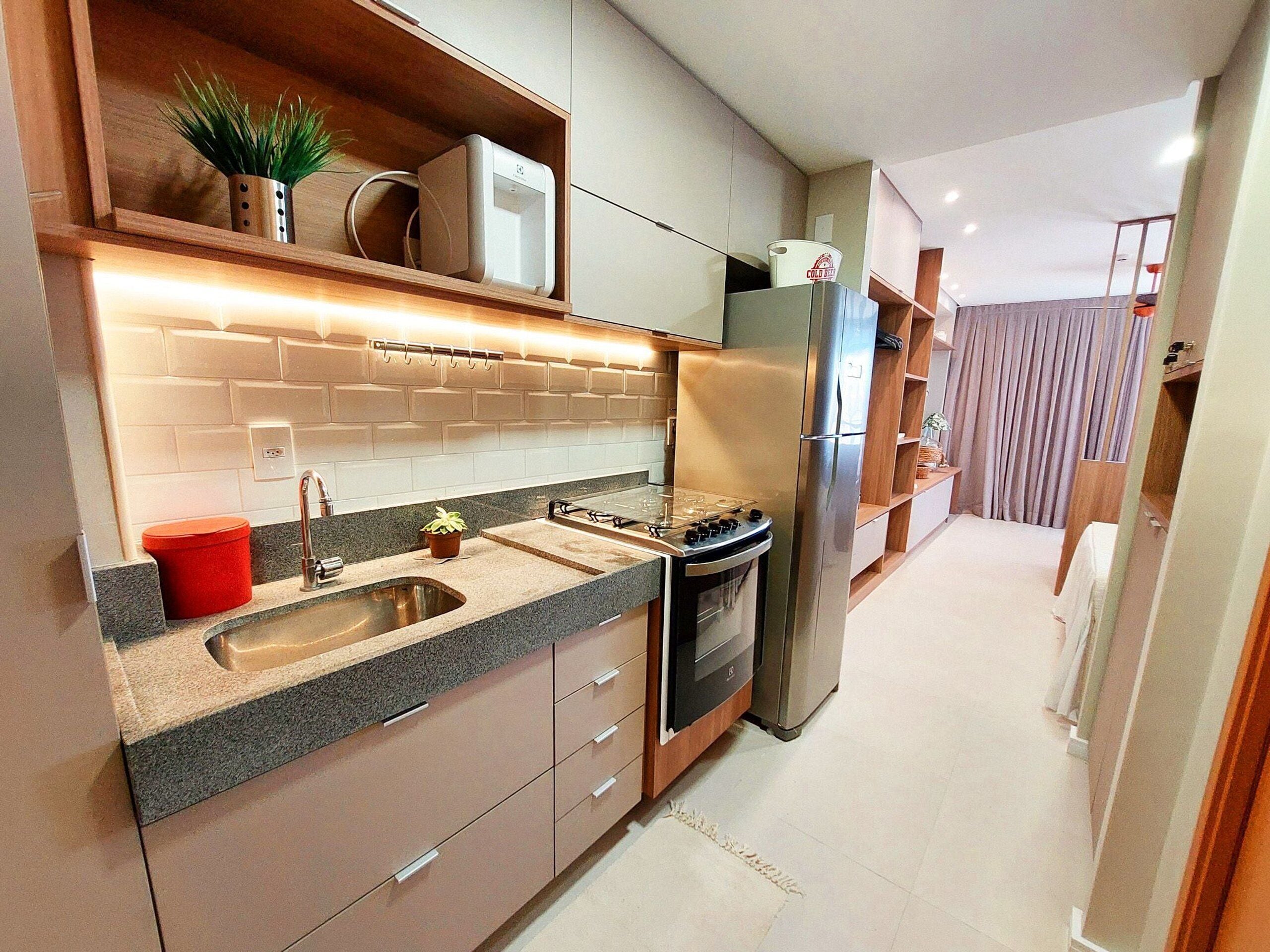A modern kitchen with a stainless steel refrigerator, built-in oven, and granite countertop.