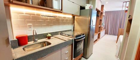 A modern kitchen with a stainless steel refrigerator, built-in oven, and granite countertop.
