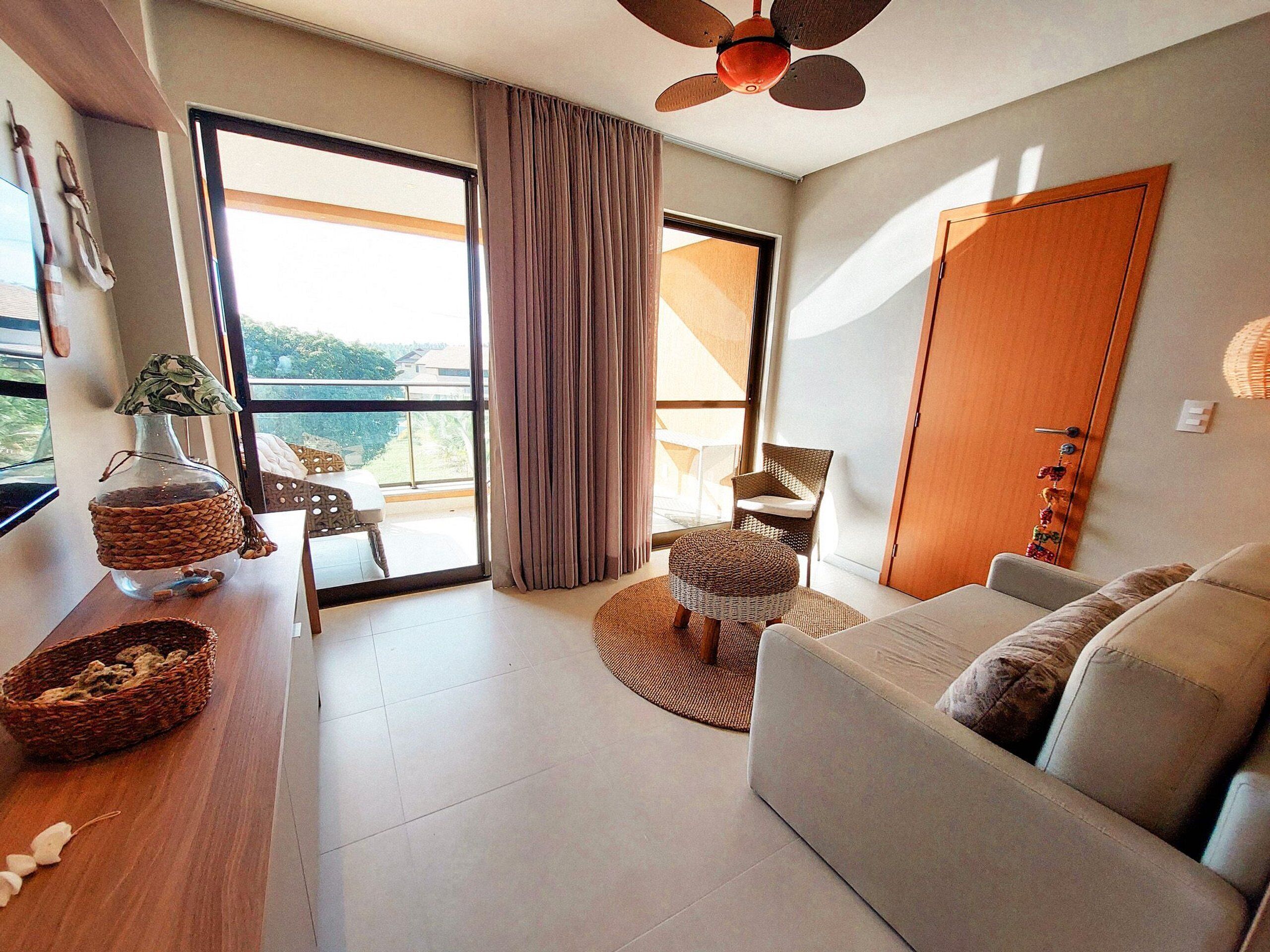 A modern living room with a sofa, a wicker coffee table, a wicker ottoman, a wicker chair, and a ceiling fan.