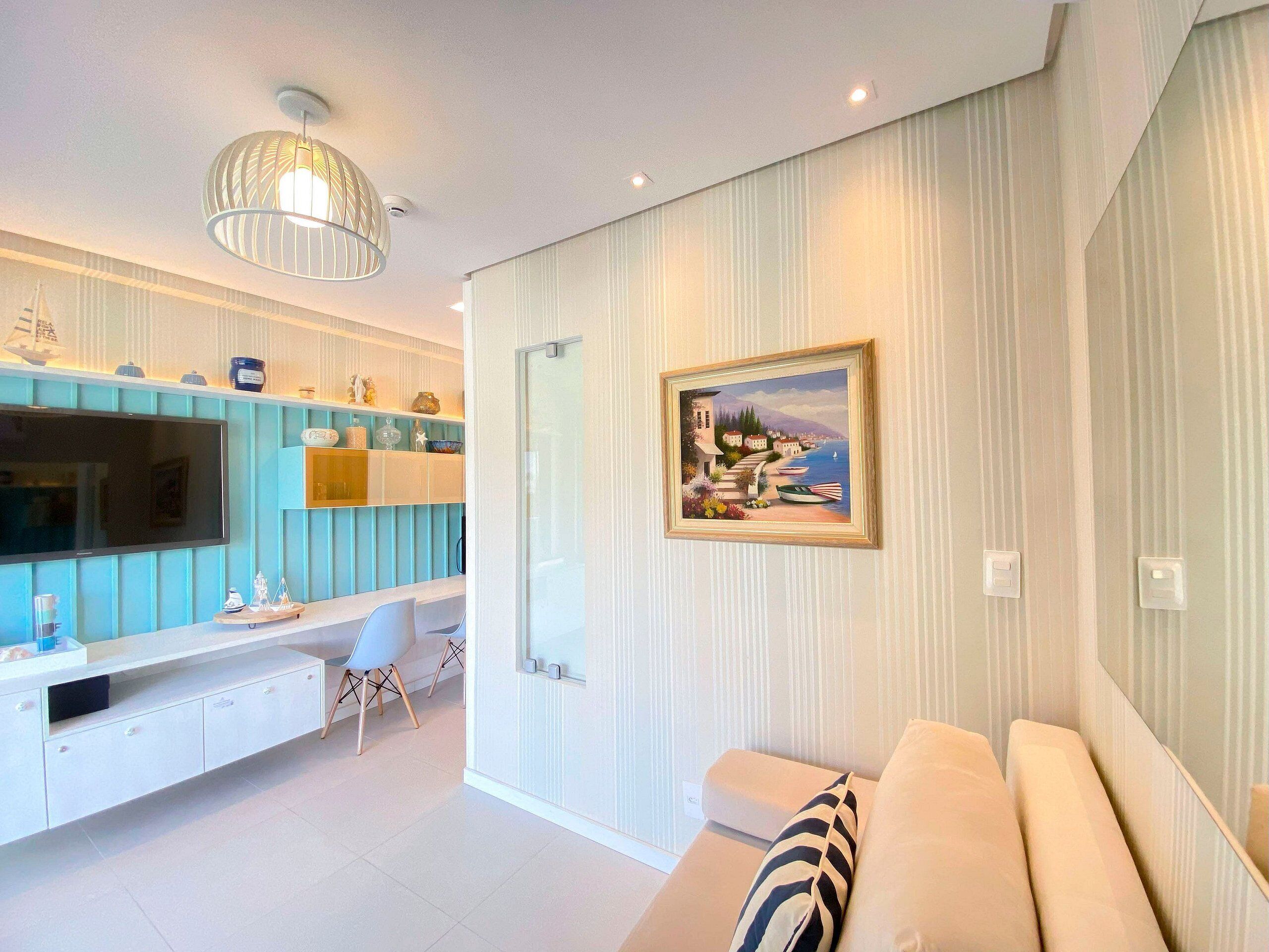 A modern living room with a TV, seating, and a painting.
