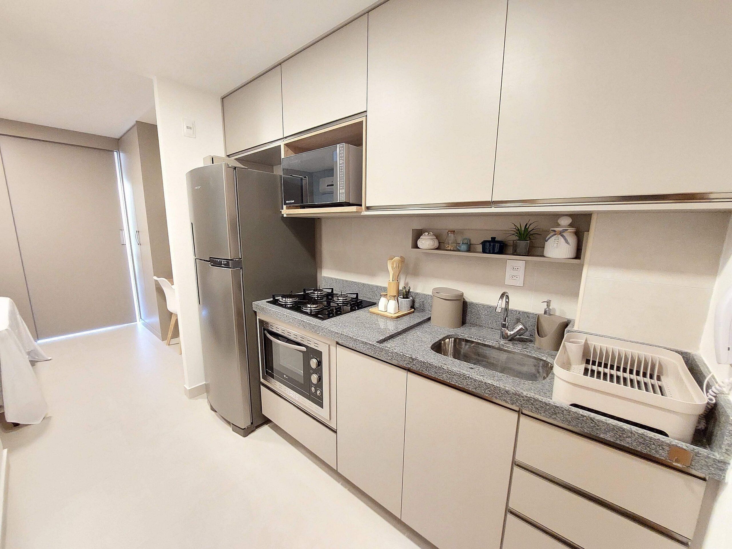 A compact kitchen with a refrigerator, stove, microwave, and a small sink.