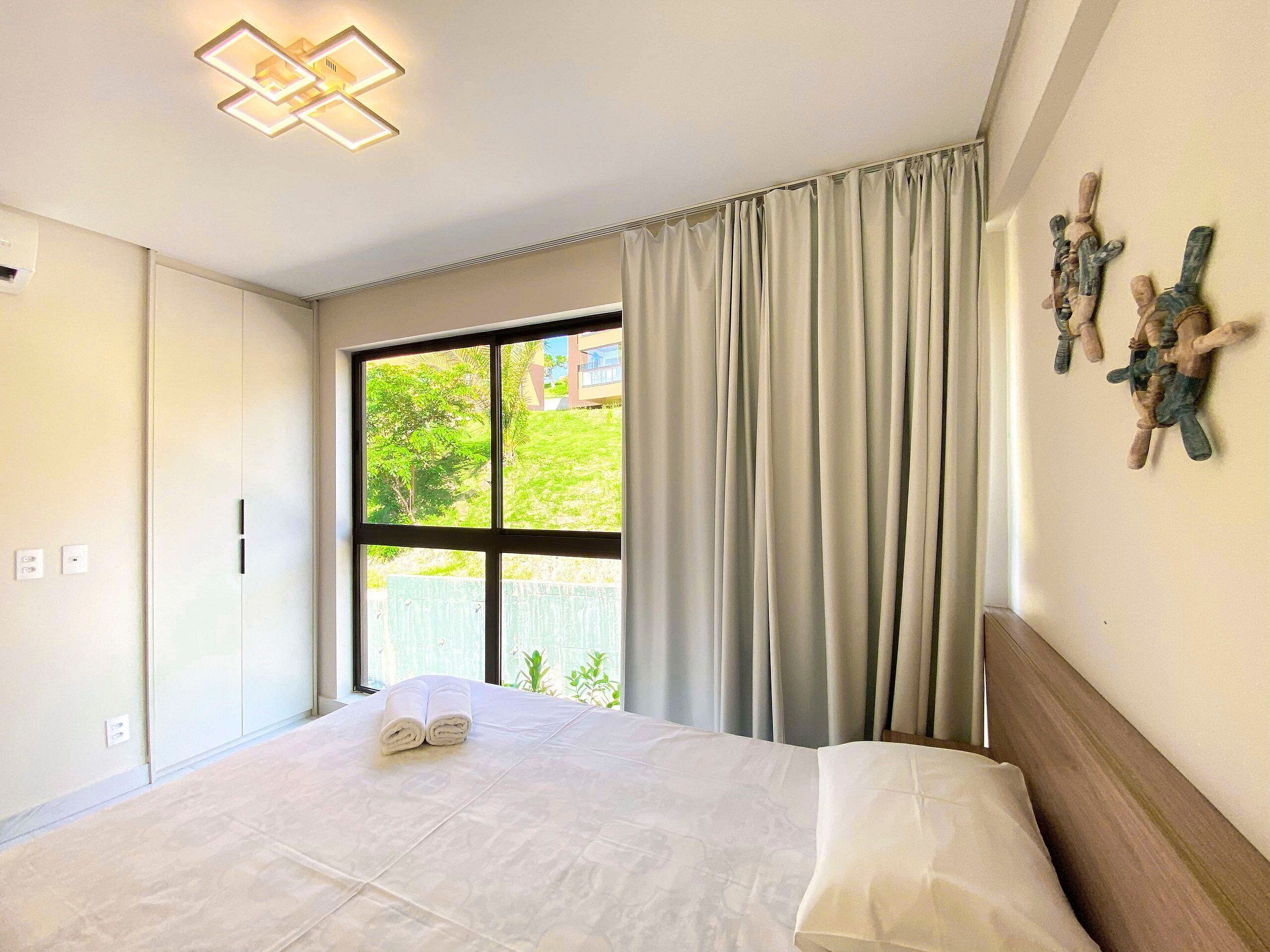 Ein Hotelzimmer mit Bett, einem Vorhangfenster, Wandkunst und einer Deckenleuchte.