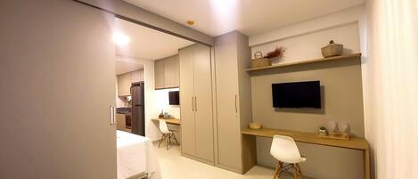 A modern bedroom with a bed, a desk, a chair, a TV, and a wardrobe.
