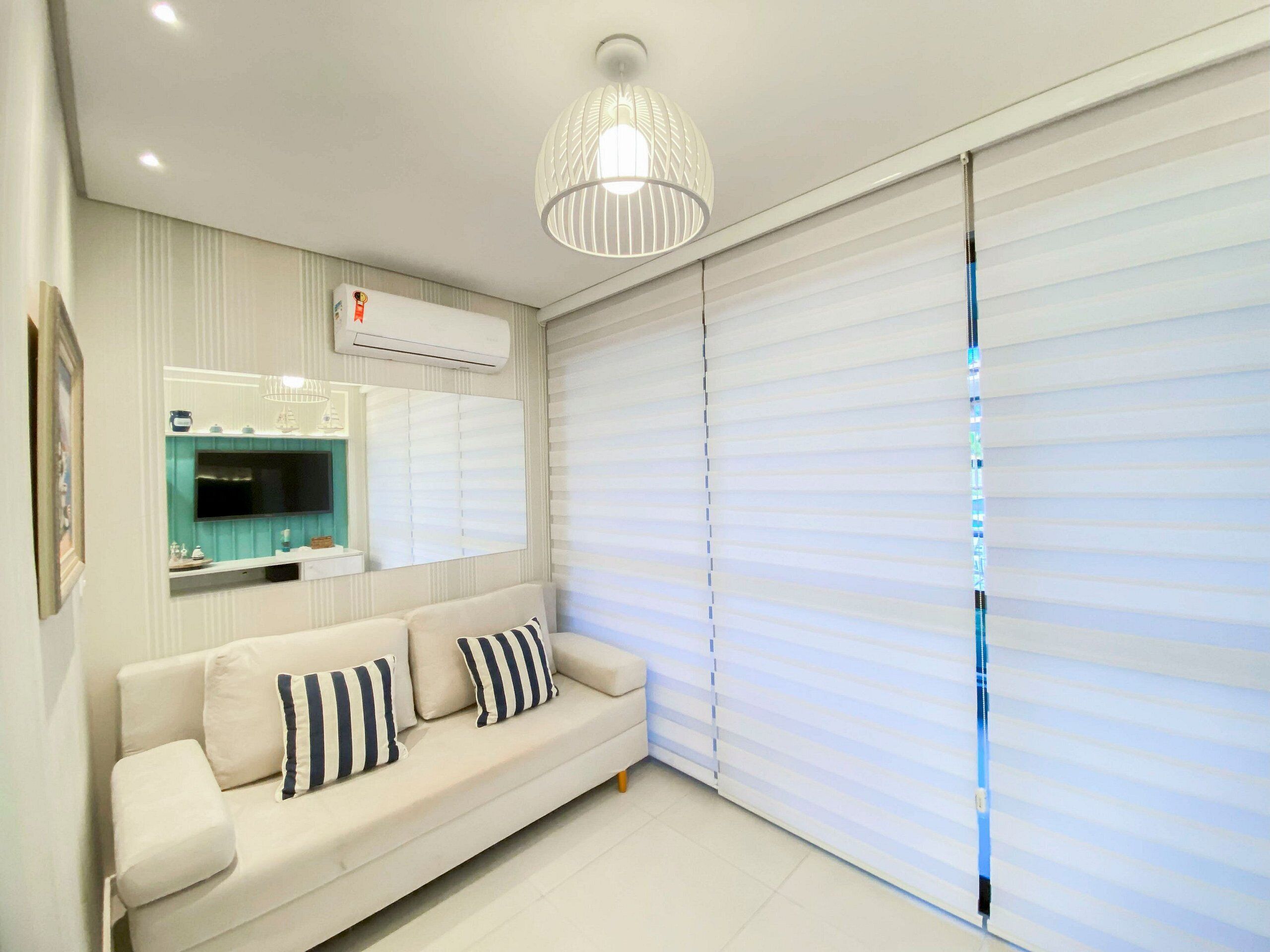 A modern living room with a sofa, a mounted TV, and a ceiling light fixture.