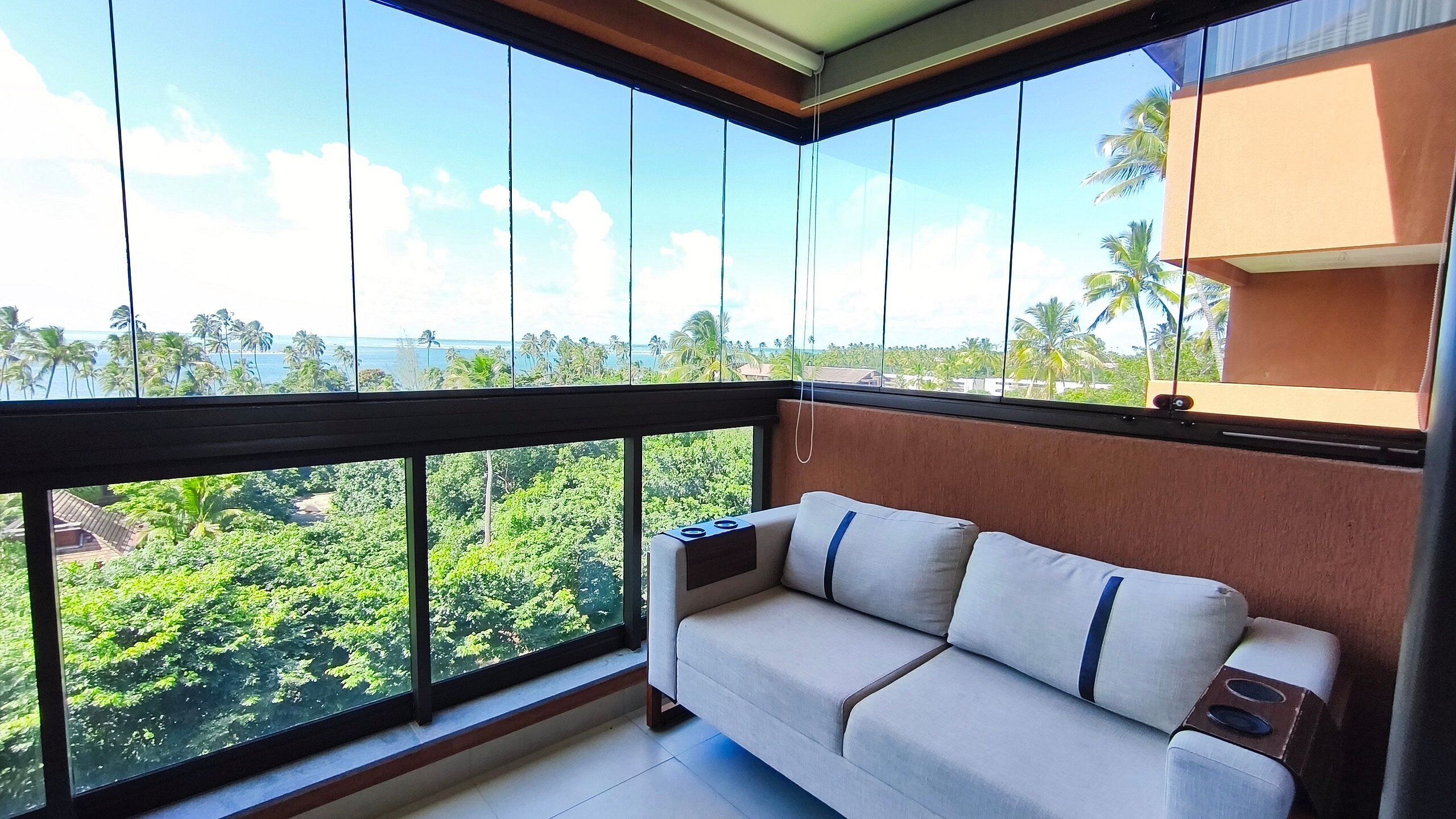 A balcony with a sofa and a view of a tropical landscape.