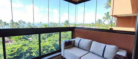 A balcony with a sofa and a view of a tropical landscape.