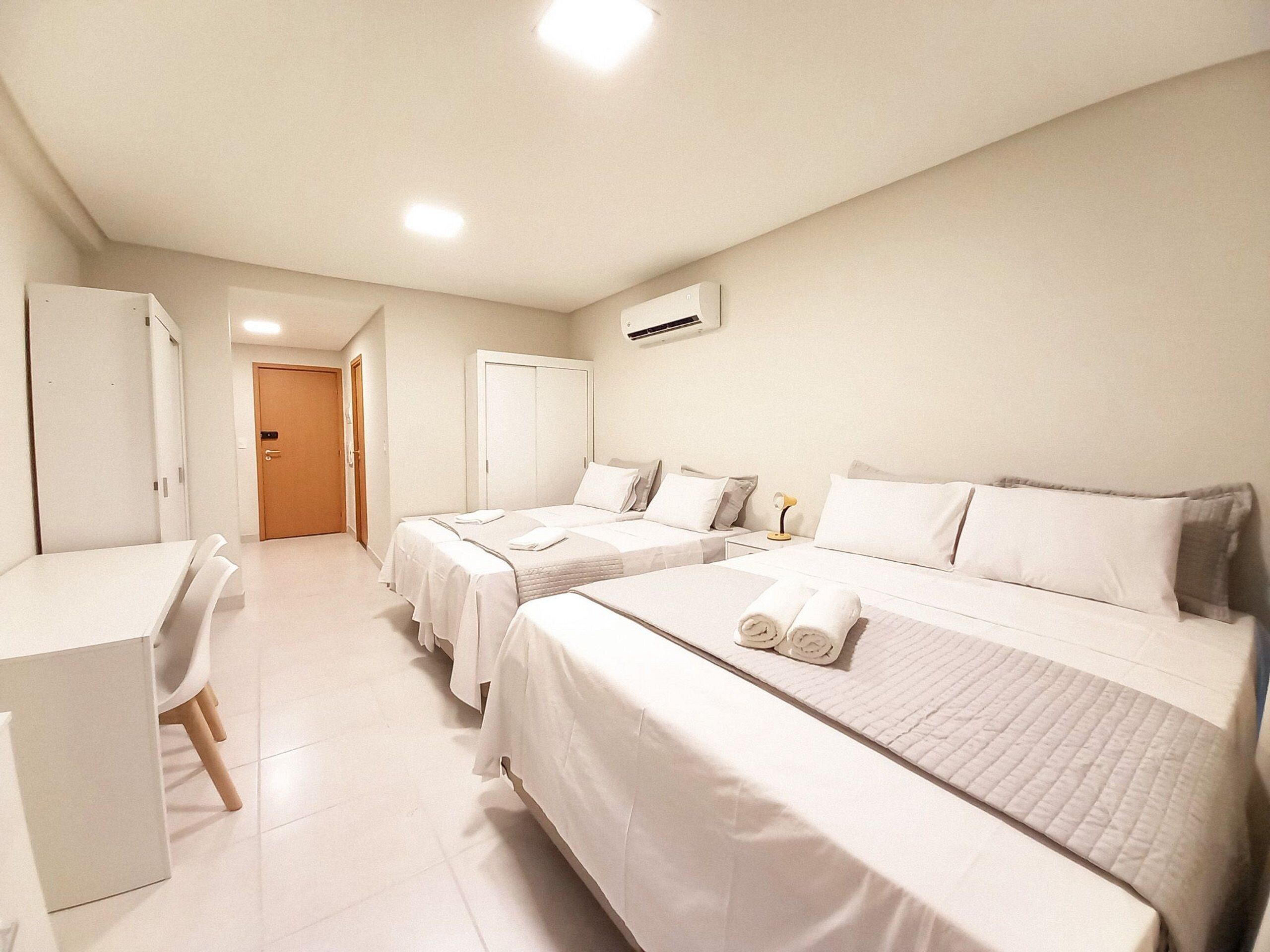 A hotel room with two beds, a desk, and a chair.