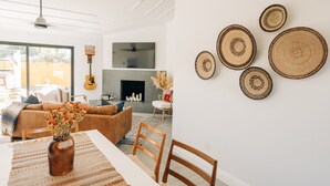 A living room with a sofa, a dining table with chairs, a guitar, and a fireplace. - Glam Designer House with a Pool, Walk to Old Town (Scottsdale)