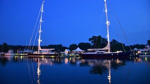 Un port de plaisance au crépuscule, où plusieurs voiliers sont amarrés.