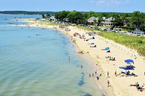 A beach with people, umbrellas, and a pier.
